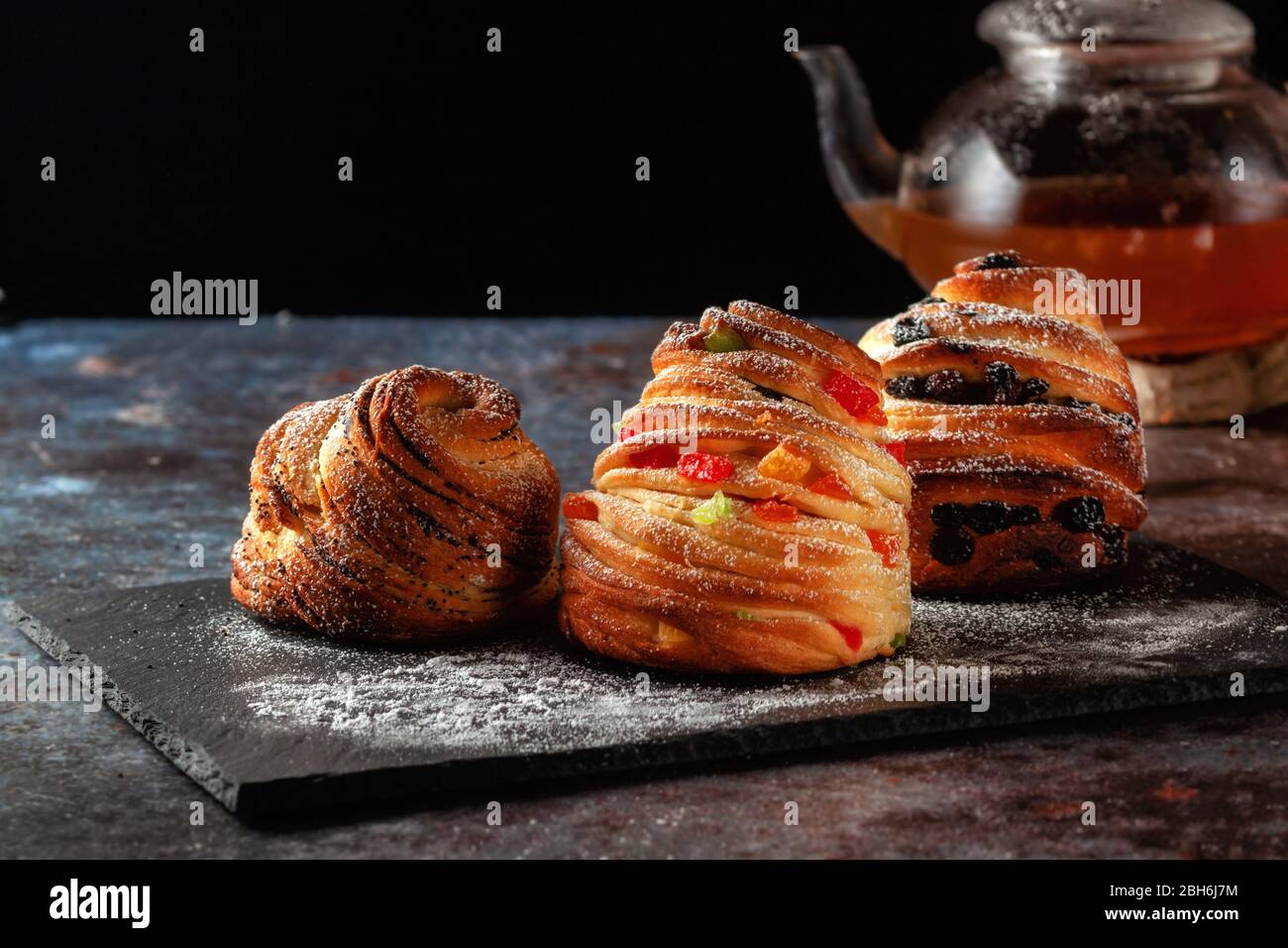 Kraffins aux raisins secs, fruits confits et graines de pavot, arrosés de sucre en poudre. Banque D'Images
