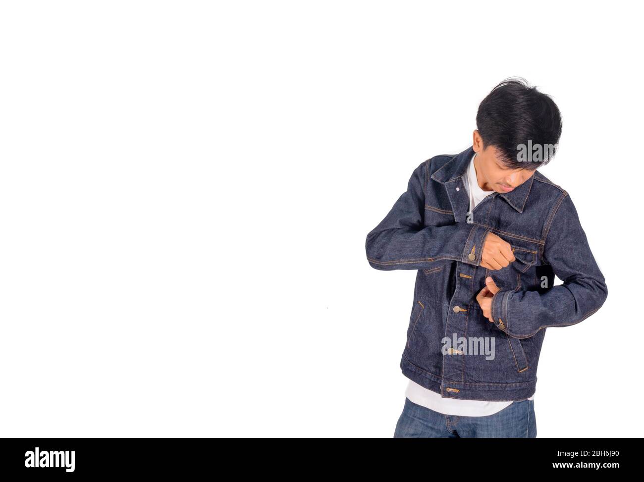 Un garçon asiatique met sur un fond blanc de veste de Jean trop grande. Banque D'Images