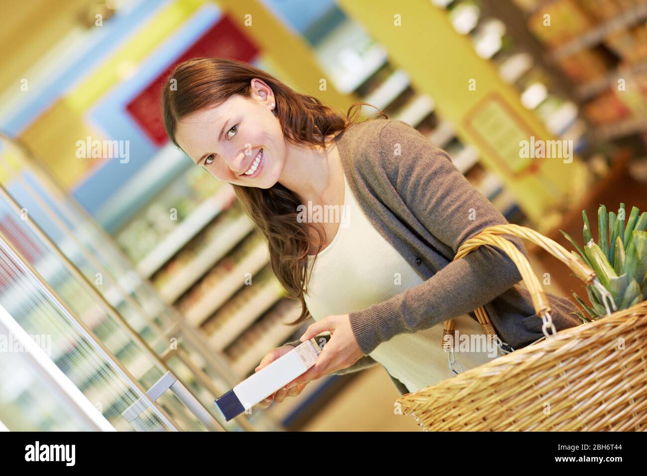 Femme souriante au supermarché avec des aliments congelés Banque D'Images