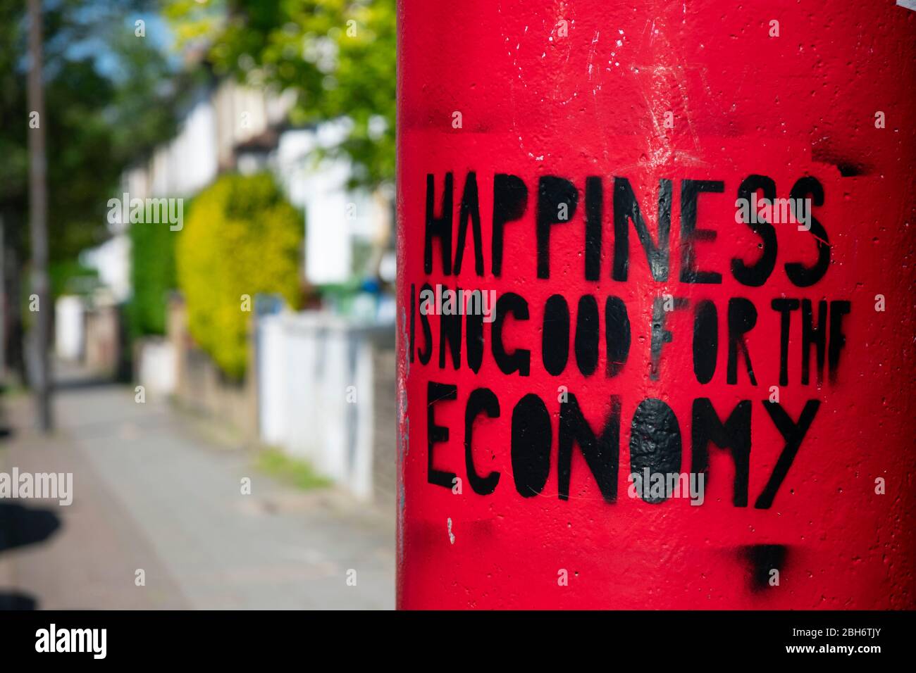 Londres / Royaume-Uni - 21 avril 2020: "Le bonheur n'est pas bon pour l'économie". Œuvres d'art locales sur une boîte postale à Honor Oak. Banque D'Images