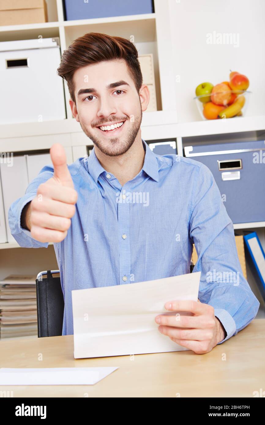 Le jeune homme avec une lettre tient son pouce vers le haut Banque D'Images