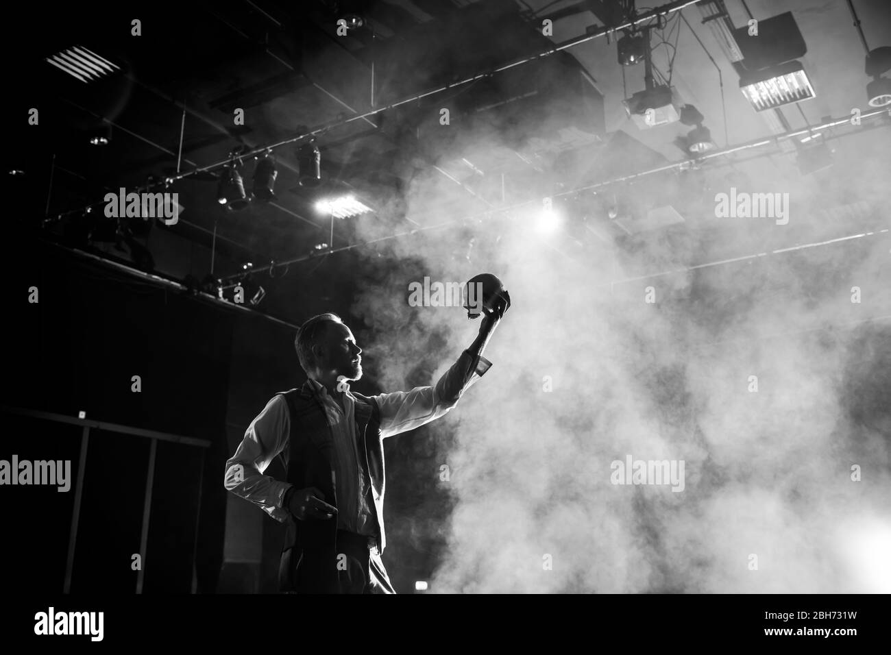 Acteur sur scène exécutant Hamlet yorik scène avec crâne, noir et blanc avec projecteur Banque D'Images