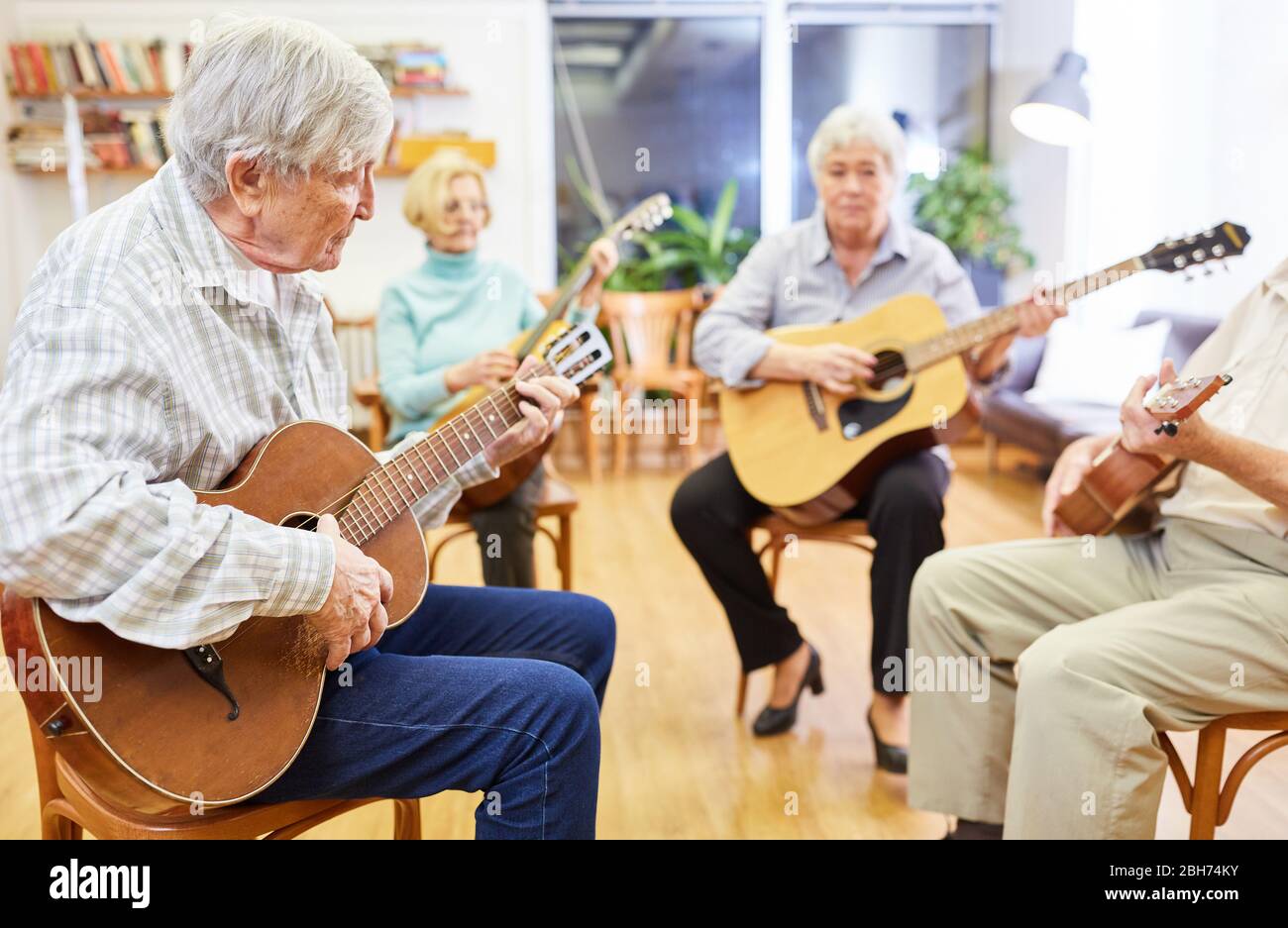Groupe d'aînés sur des cours de guitare dans leur temps libre ou comme ergothérapie Banque D'Images