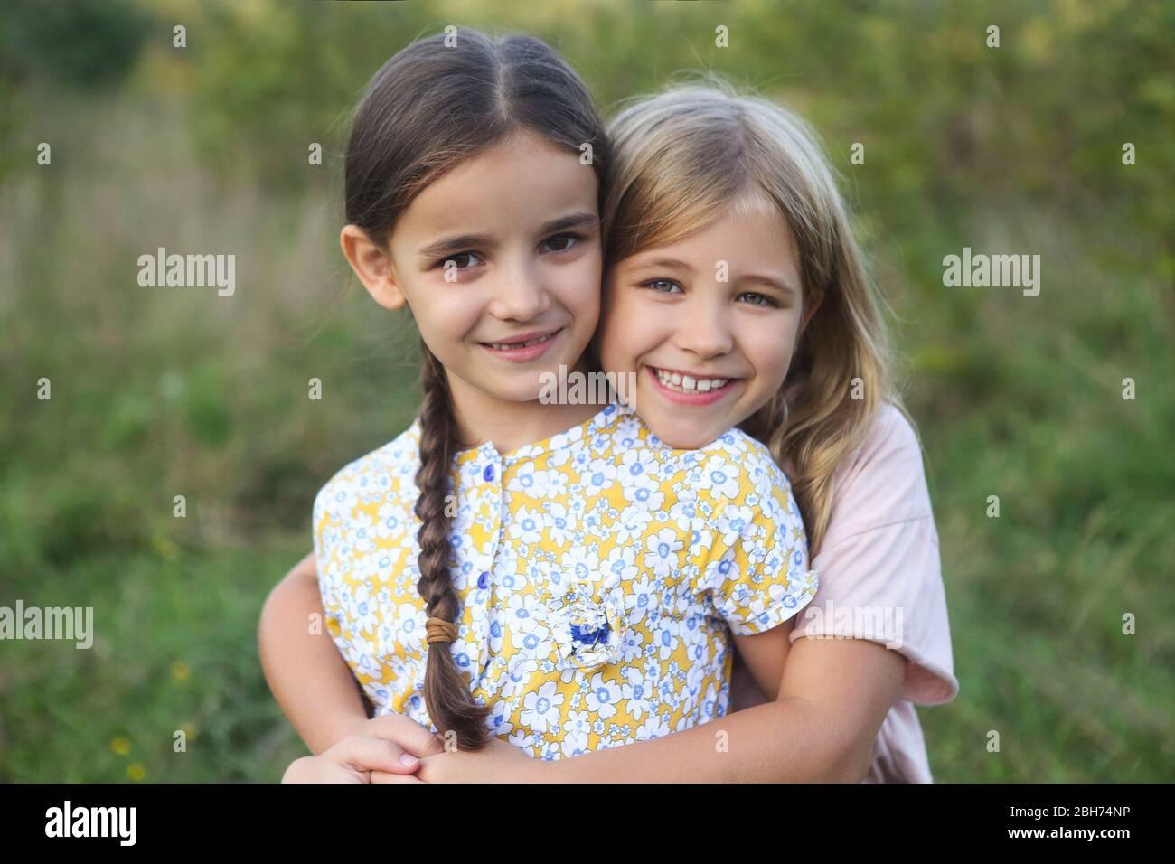 Portrait des filles blondes et noires aired heureux riant et se câlin au coucher du soleil Banque D'Images