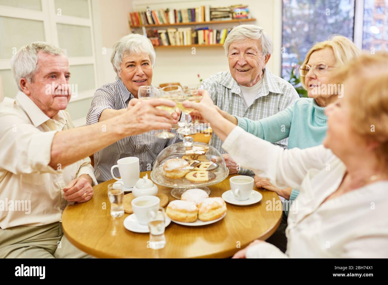 Les aînés toastent avec un verre de vin blanc et célèbrent ensemble un anniversaire Banque D'Images