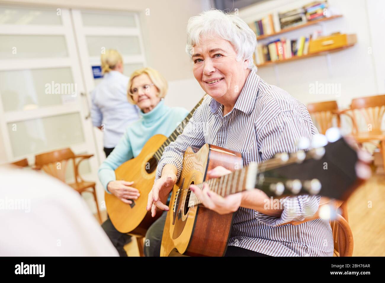 Une femme âgée souriante prend des cours de guitare dans un cours de lycée folklorique Banque D'Images