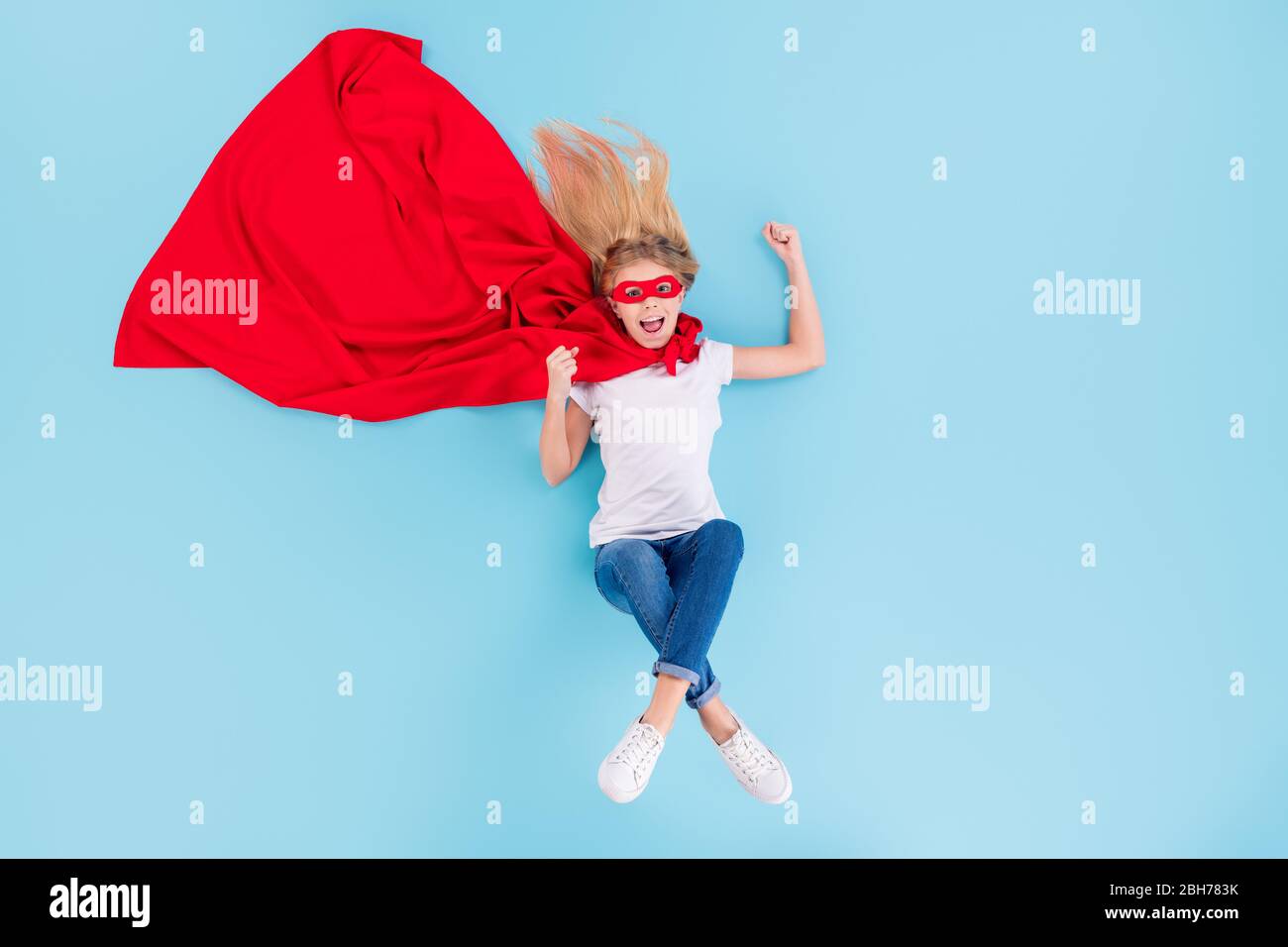 Haut au-dessus de la vue haute angle pleine photo de l'enfant fou enchanté petite superfemme sauver le monde lever les poings oui porter le masque de cape rouge blanc denim Banque D'Images