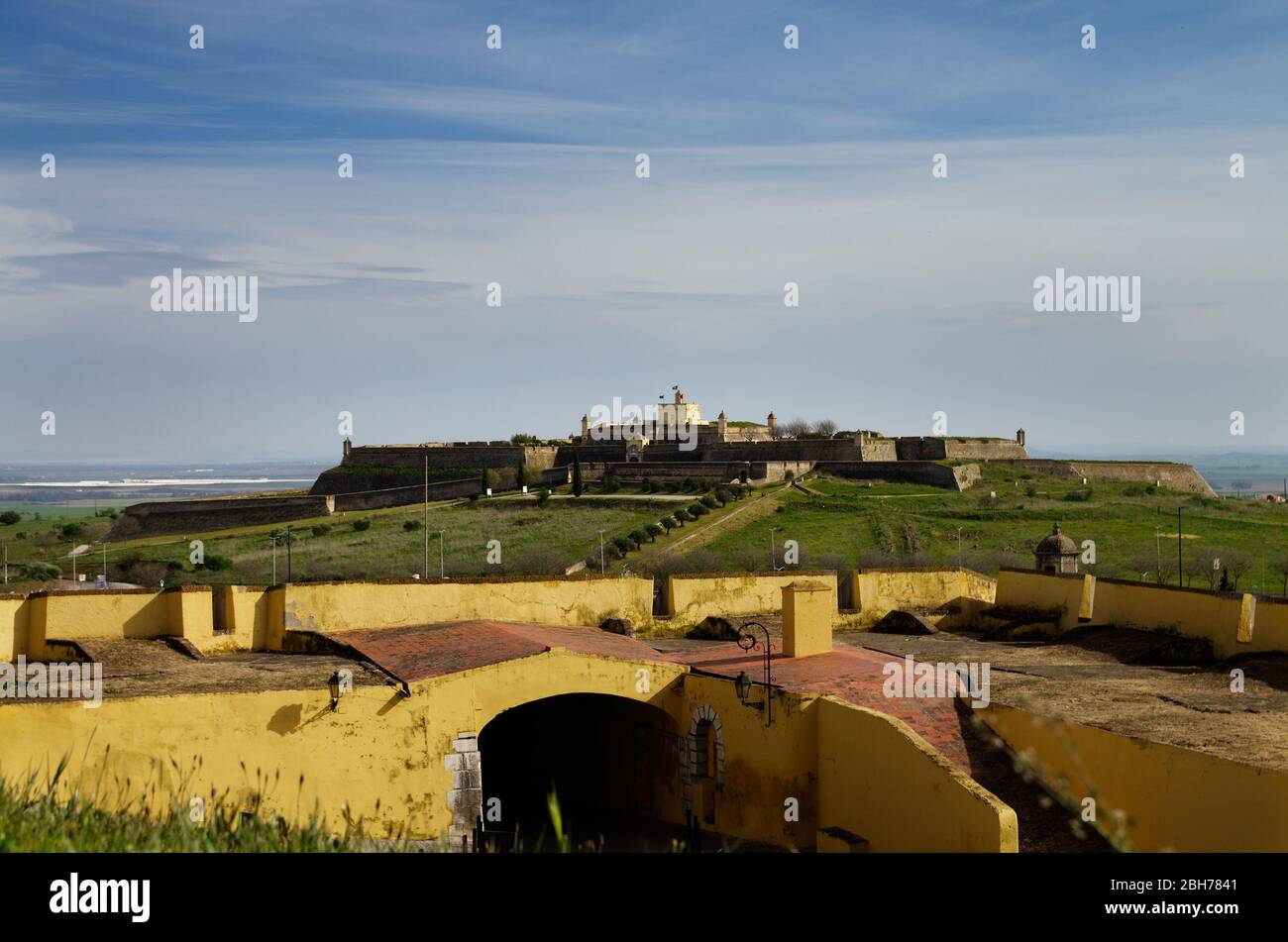 Forteresse de Santa Luzia au sommet d'une petite colline vue de derrière les murs défensifs jaunes de la ville d'Elvas. Ciel bleu nuageux. Alentejo, Portugal. Banque D'Images