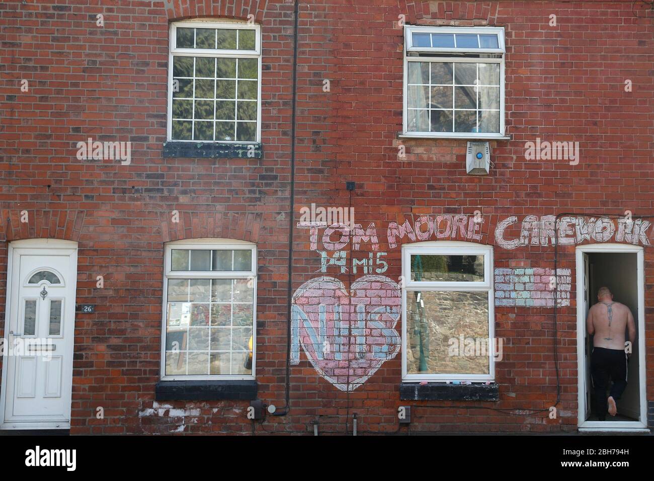 Anstey, Leicestershire, Royaume-Uni. 24 avril 2020. Un homme entre dans une maison avec un hommage au NHS et au capitaine Tom Moore pendant le verrouillage de la pandémie de coronavirus. Credit Darren Staples/Alay Live News. Banque D'Images