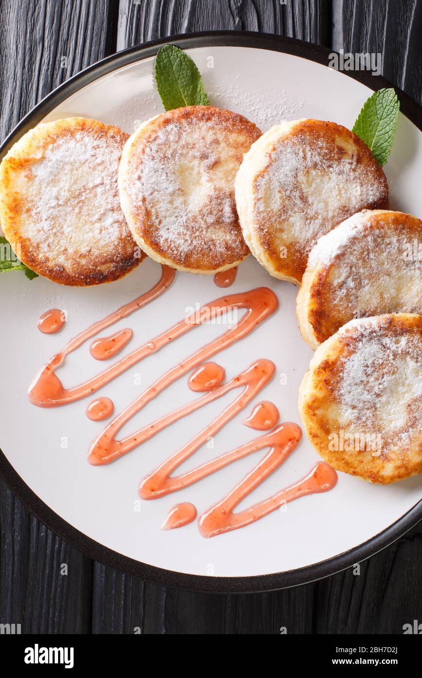 Le sirop servi avec du sucre en poudre et de la confiture de baies se ferme dans une assiette sur la table. Vue verticale du dessus Banque D'Images