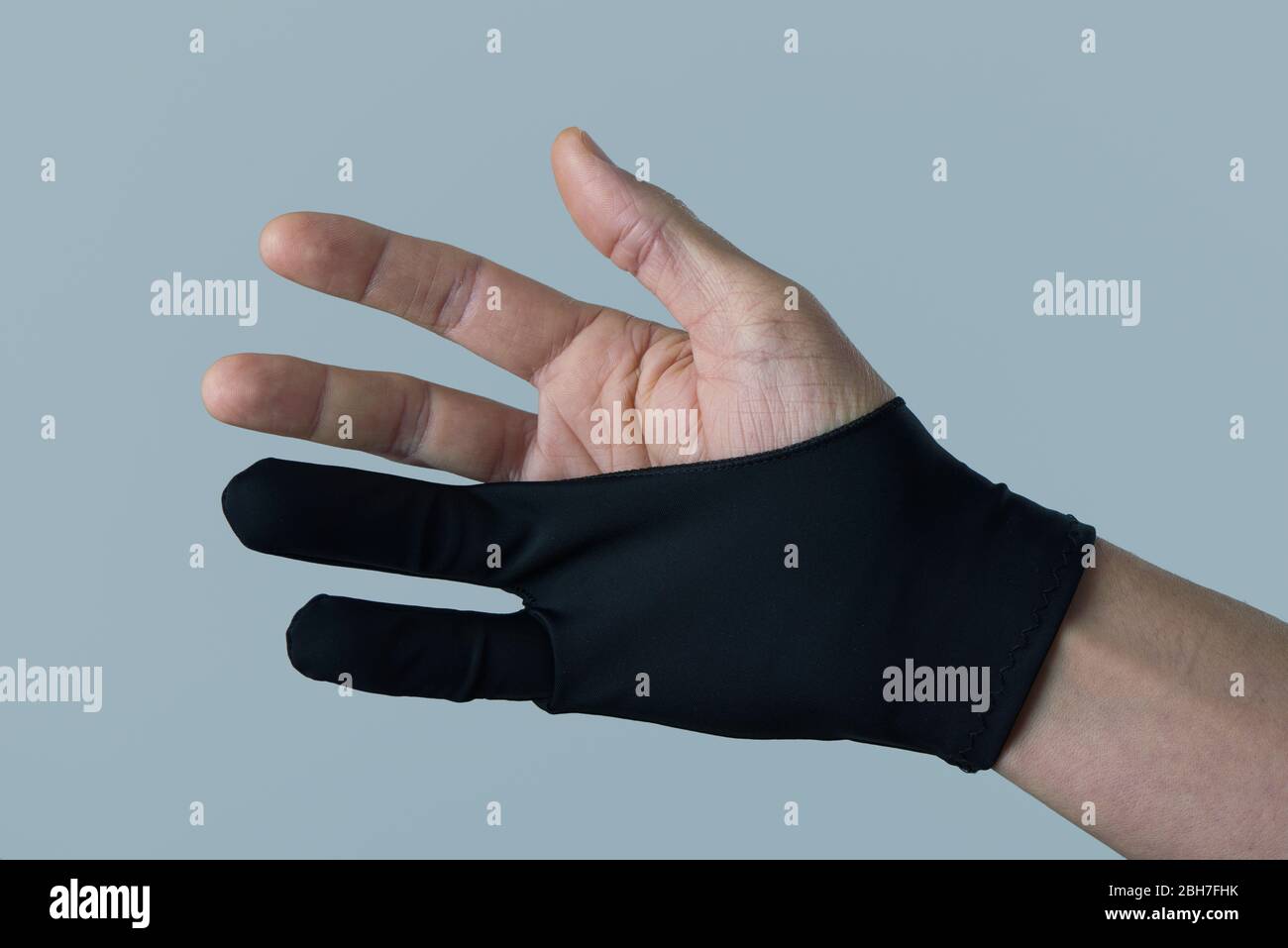 gros plan d'un homme caucasien portant un gant noir à deux doigts sur un fond gris Banque D'Images