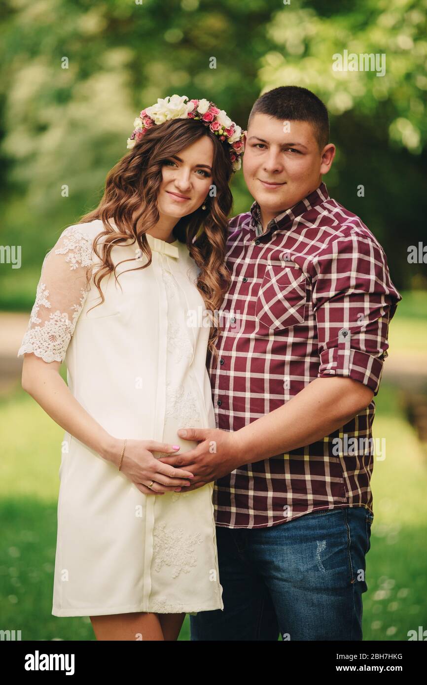 Jeune couple romantique de grossesse sur la nature dans le parc d'été. Femme enceinte attendant un bébé. Future maman et papa, famille. Mère, fête des pères. Banque D'Images