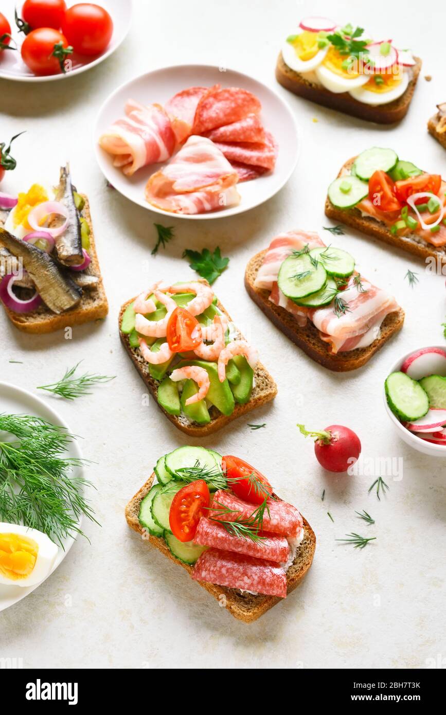 Sandwichs à surface ouverte avec viande, légumes, fruits de mer sur fond de pierre légère. En-cas savoureux et sains. Banque D'Images