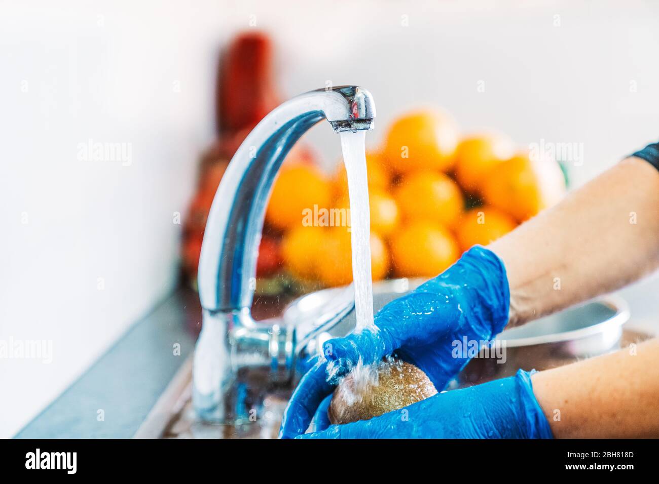 Mains avec gants en latex bleu, désinfectant un kiwi pour décontaminer le  fruit du coronavirus. Laver les fruits dans l'évier de cuisine avec de  l'eau et du lessive Photo Stock - Alamy