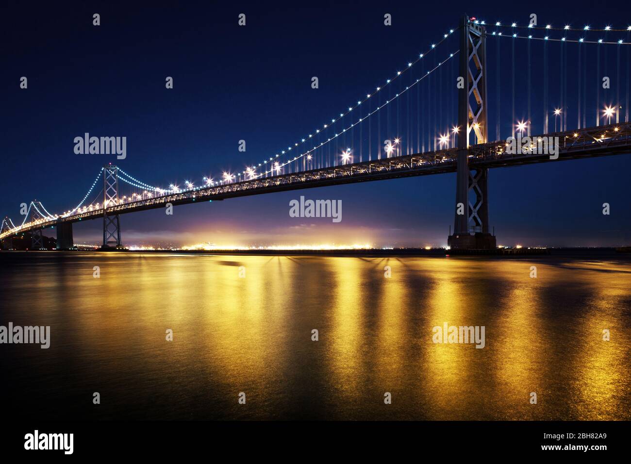 Une longue exposition du Bay Bridge à San Francisco la nuit avec des lumières réfléchissantes sur l'eau Banque D'Images