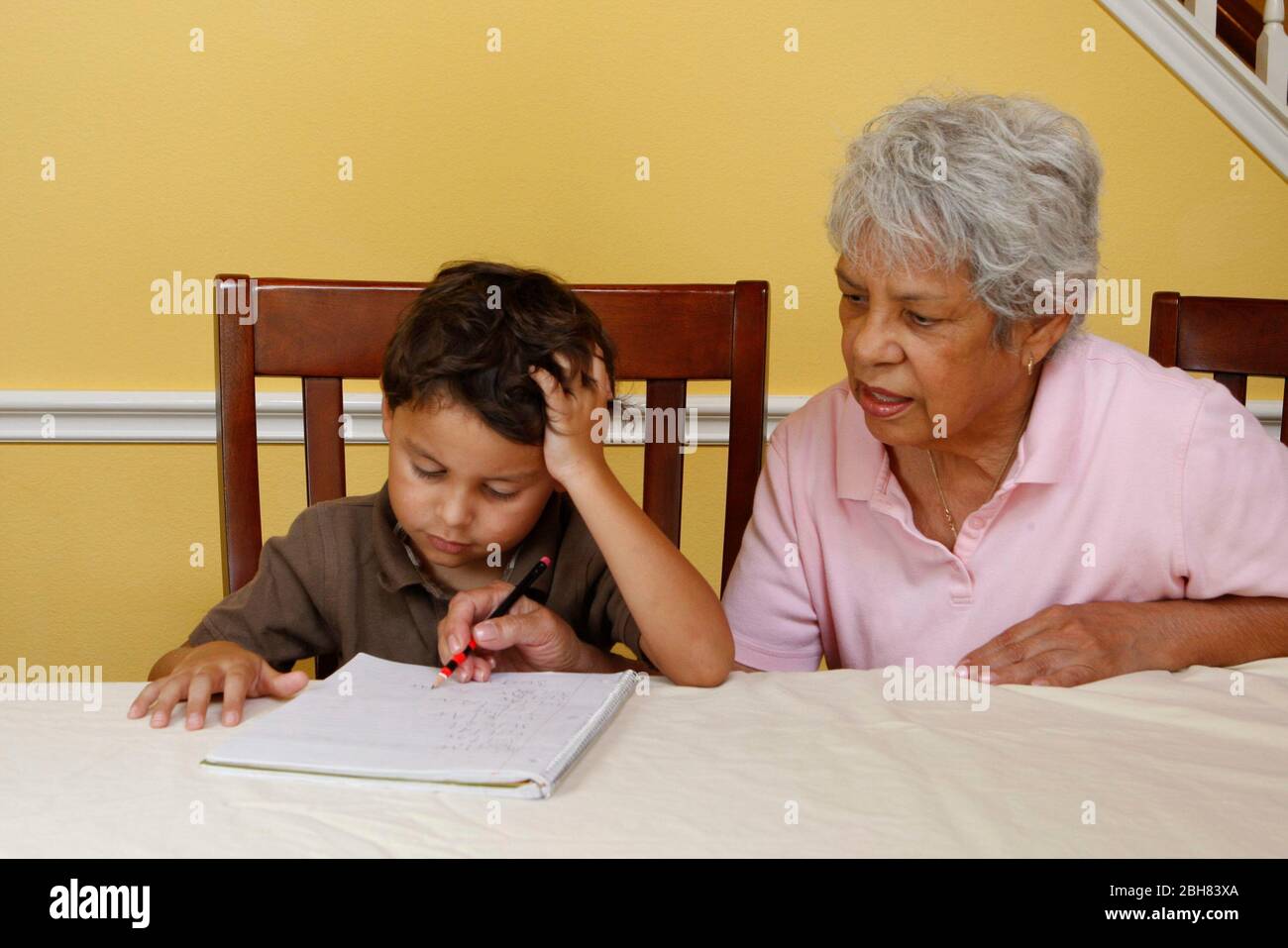 Austin, Texas États-Unis, 22 août 2009: Garçon mexicain-américain de cinq ans pratiquant l'écriture à la maison tandis que sa grand-mère observe et aide. M. ©Bob Daemmrich Banque D'Images