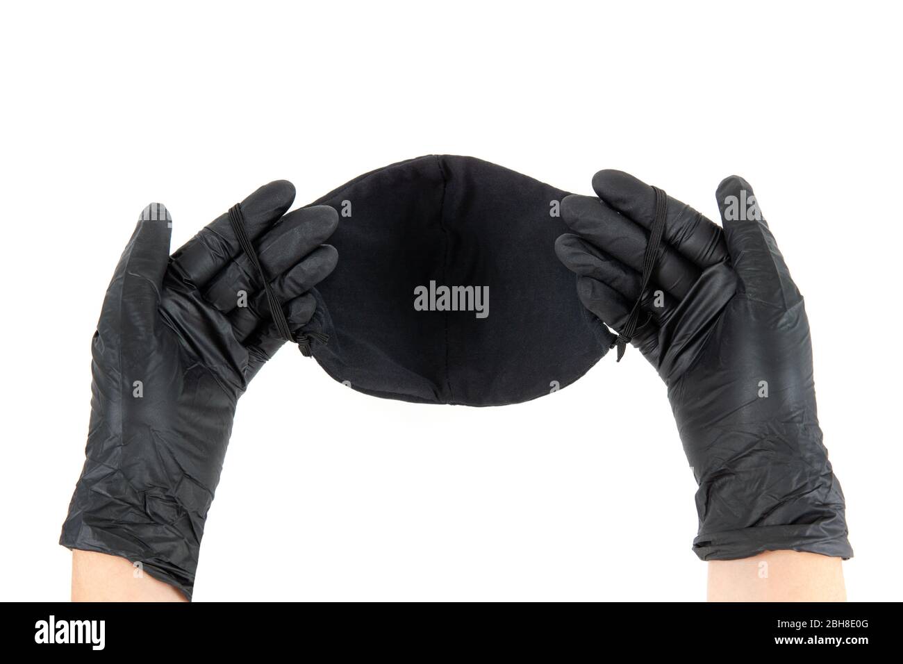 Les mains féminines dans des gants jetables noirs contiennent un masque noir réutilisable en coton. Vue de la première personne, isolée sur blanc. Banque D'Images