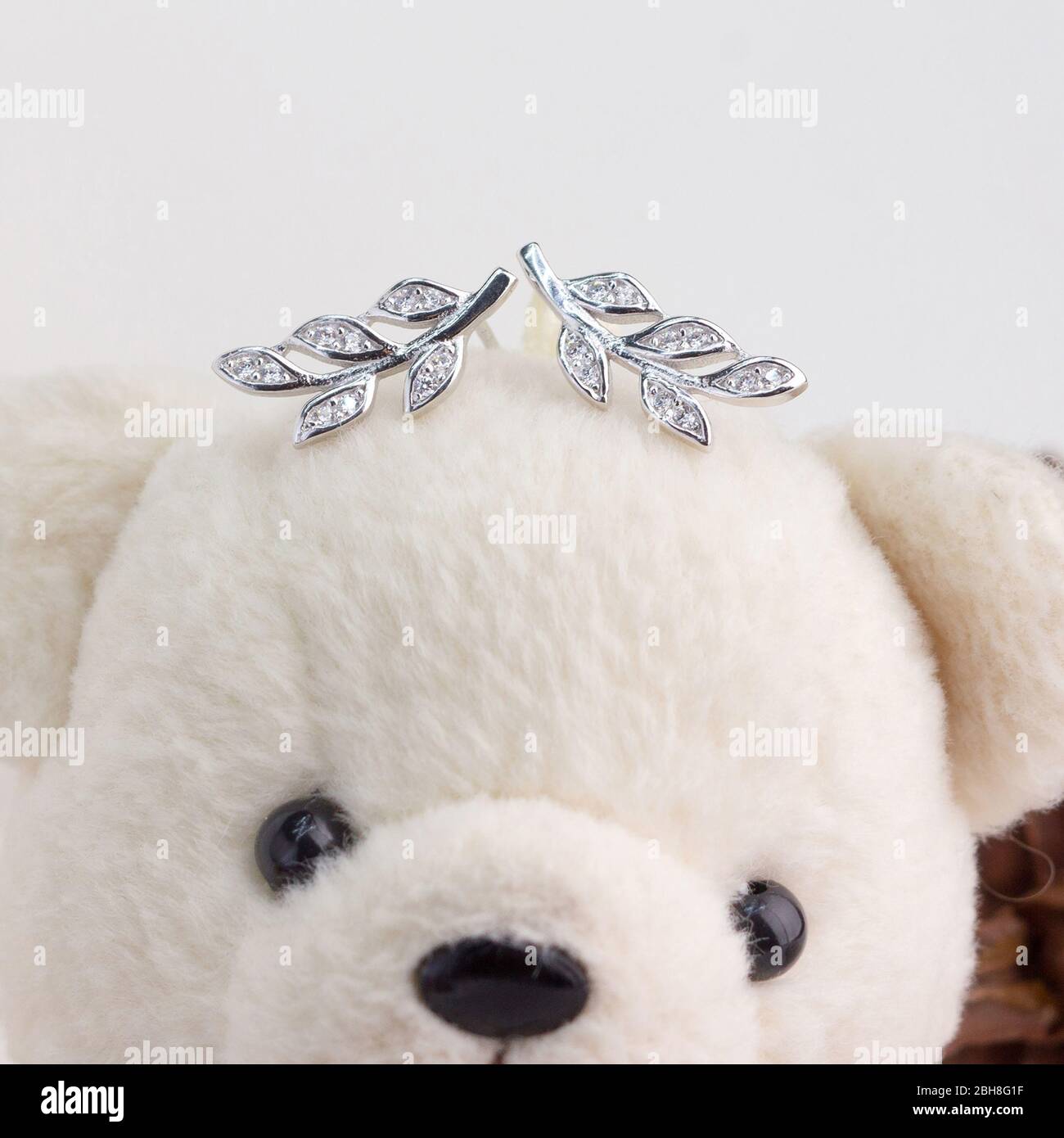 Une paire de superbes boucles d'oreilles en argent 925 en forme de feuilles décorées de diamants s'affichent sur l'ours en peluche Banque D'Images