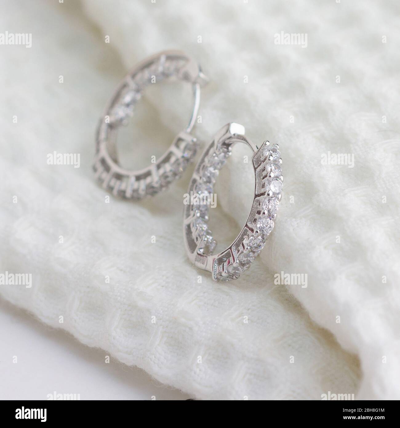 Une paire de superbes boucles d'oreilles en argent 925, décorées de diamants sur un tissu blanc Banque D'Images