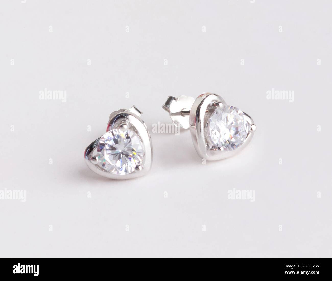 Une paire de superbes boucles d'oreilles en argent 925 en forme de coeur décorées de diamant isolé sur fond blanc Banque D'Images