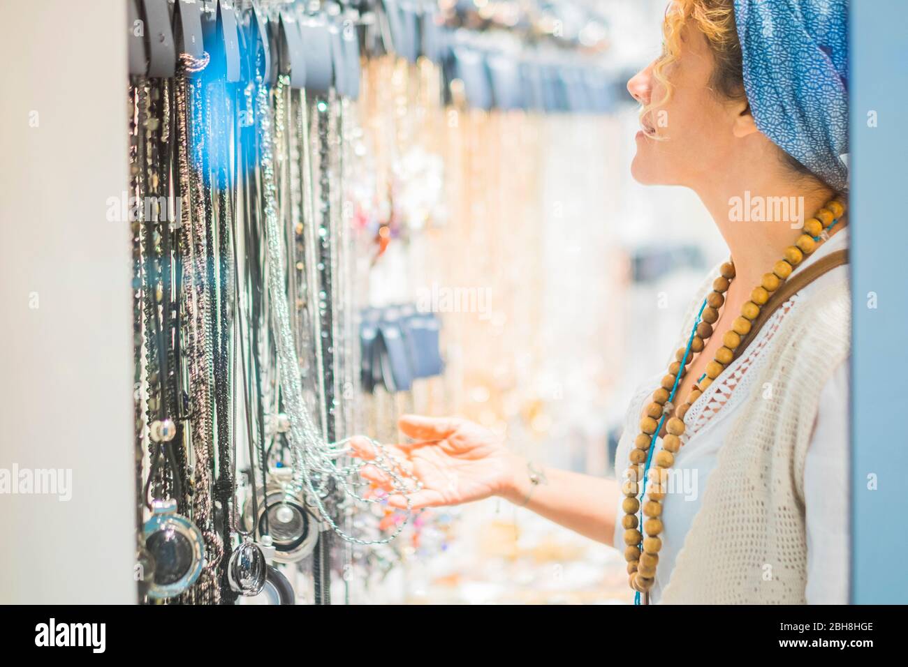 Femme recherchant et choisissant des bijoux et des accessoires à porter pour la vie nocturne avec des amis - fashion concept Store tendance avec des gens achetant à l'intérieur Banque D'Images