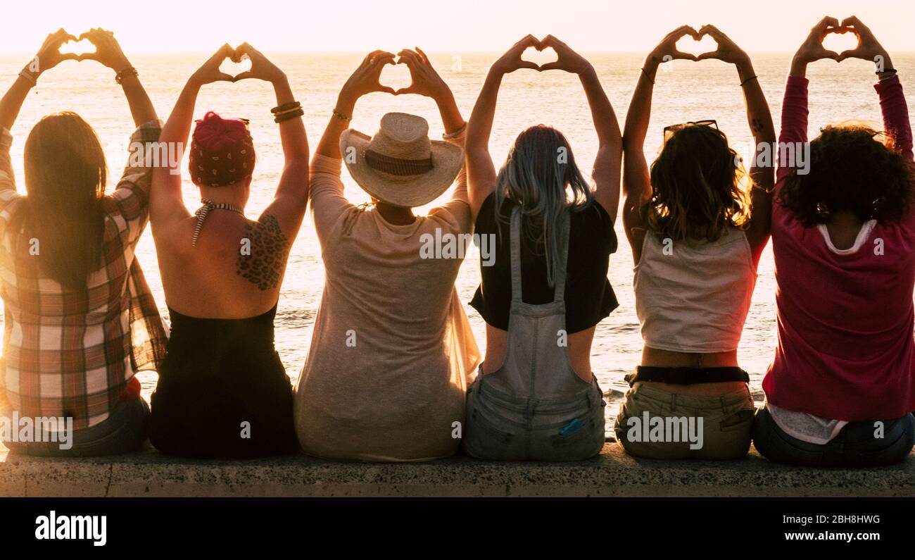 L'amour et la méditation concept de style de vie - groupe de femmes regardant le coucher du soleil sur l'océan et faire le coeur avec les mains - romantique lumière dorée et le concept de jour de Valentin - l'amitié pour toujours Banque D'Images