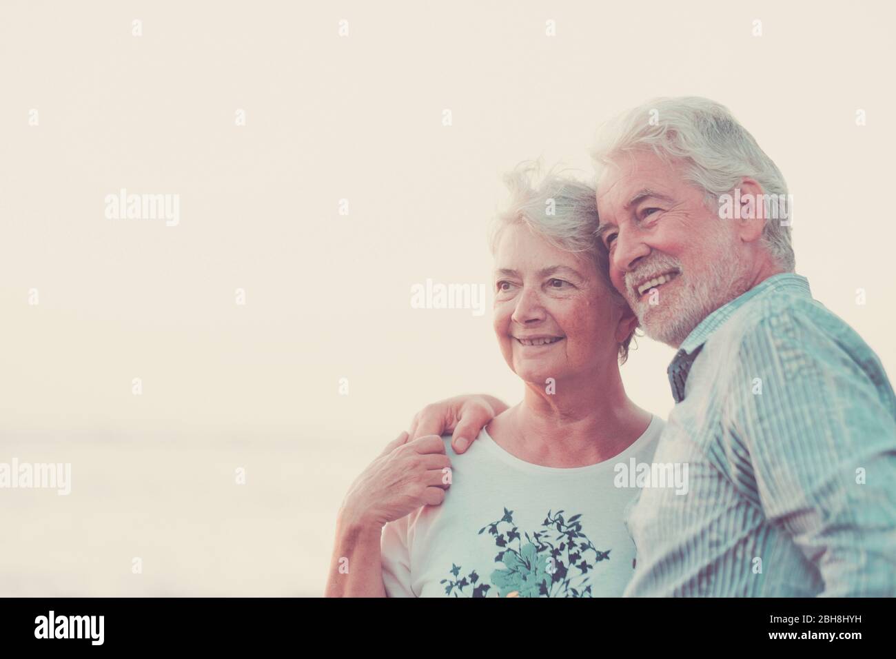 Des adultes souriants et souriants se sourient et s'aiment les uns les autres - concept de vacances, tourisme, voyage et gens - un couple senior heureux sur la plage de galets rigolent et plaisantent. Cheveux blancs et image de la société d'argent Banque D'Images