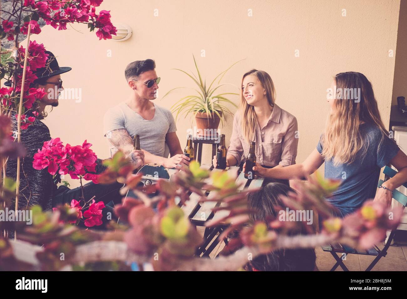 groupe de personnes boivent la bière ensemble sur la terrasse extérieure. longboard pour represente alternative traveler et les jeunes hommes et les hommes branchés. belle scène avec deux belles blondes et deux gars Banque D'Images