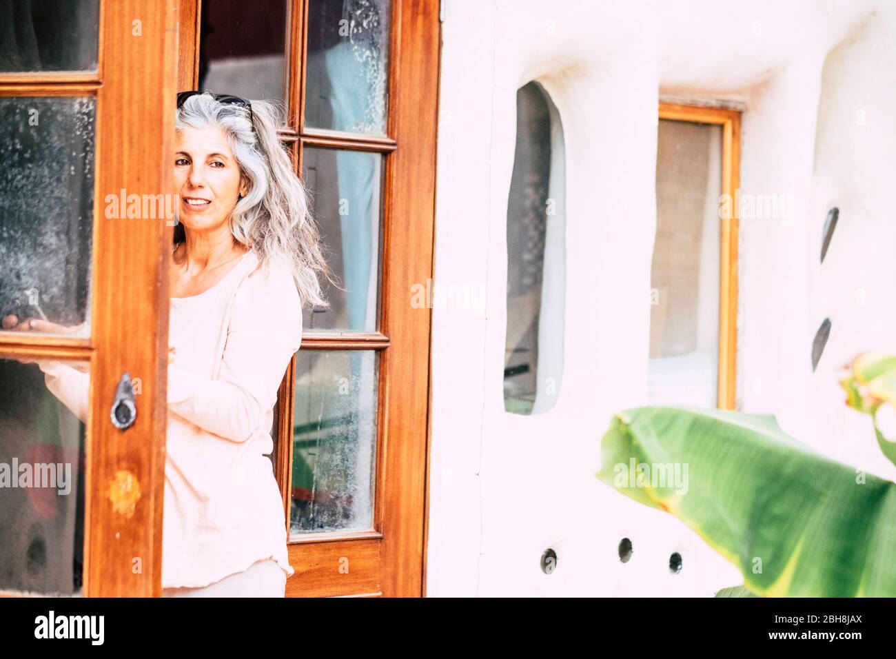 Société Silver personnes adultes caucasien femme avec de longs cheveux blancs regardant à l'extérieur de la maison de porte ouverte - alternative diversité personnes concept - portrait de jolie femme âge Banque D'Images