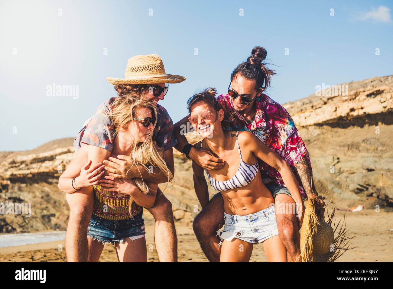 Les gens joyeux deux couples rigolent et s'amusent ensemble - les amis qui apprécient les vacances d'été au berach - les filles transportant des garçons - les jeunes hommes et les femmes de belle jouer dans une amitié heureuse Banque D'Images