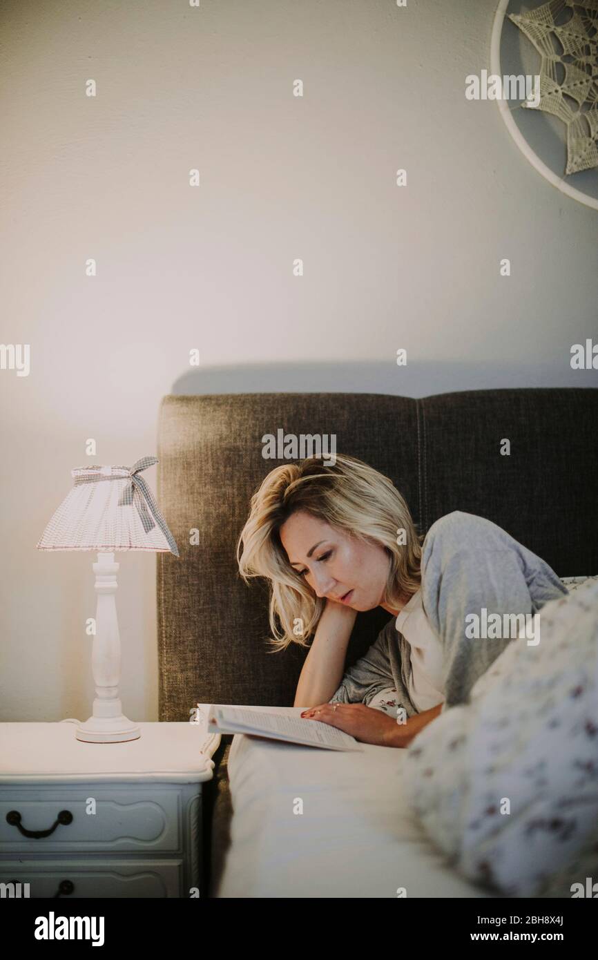 Frau liegt mit Buch im Bett Banque D'Images