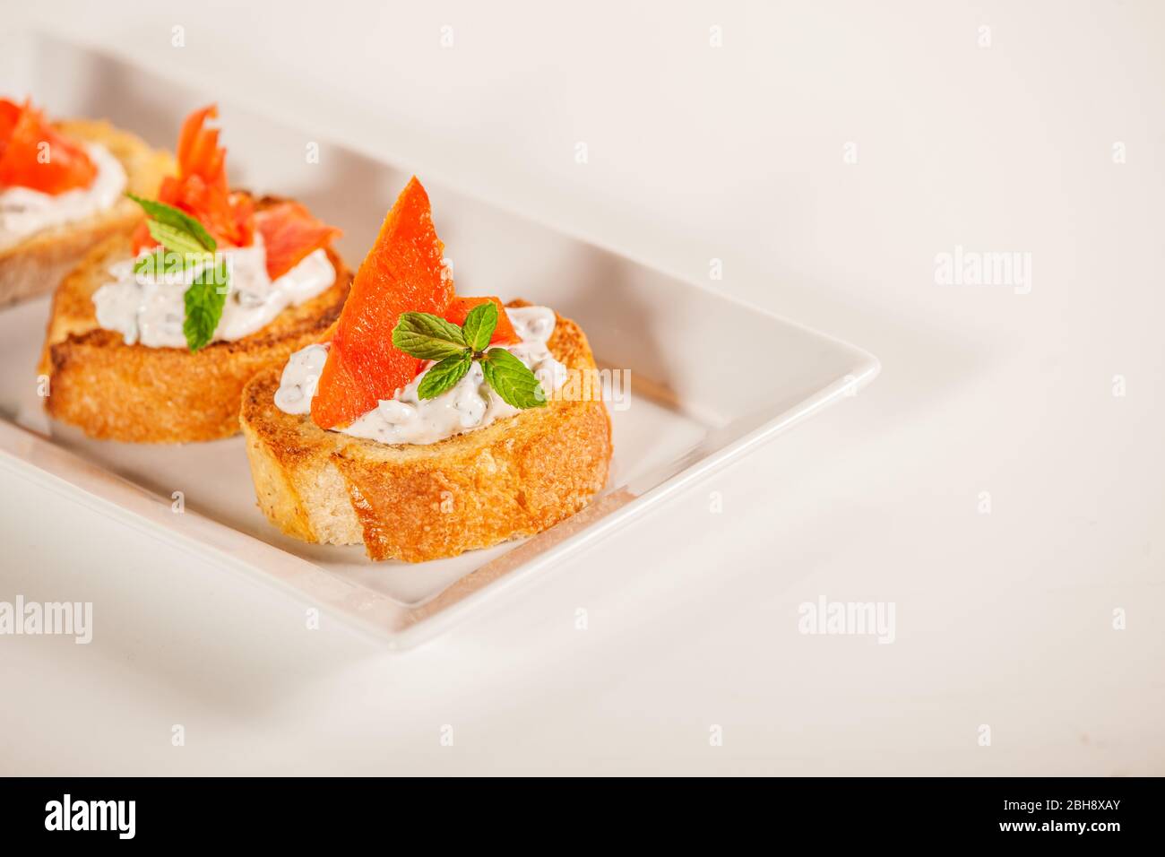 Assiette de poisson de saumon décoratif sur l'apéritif de la bruschetta Banque D'Images