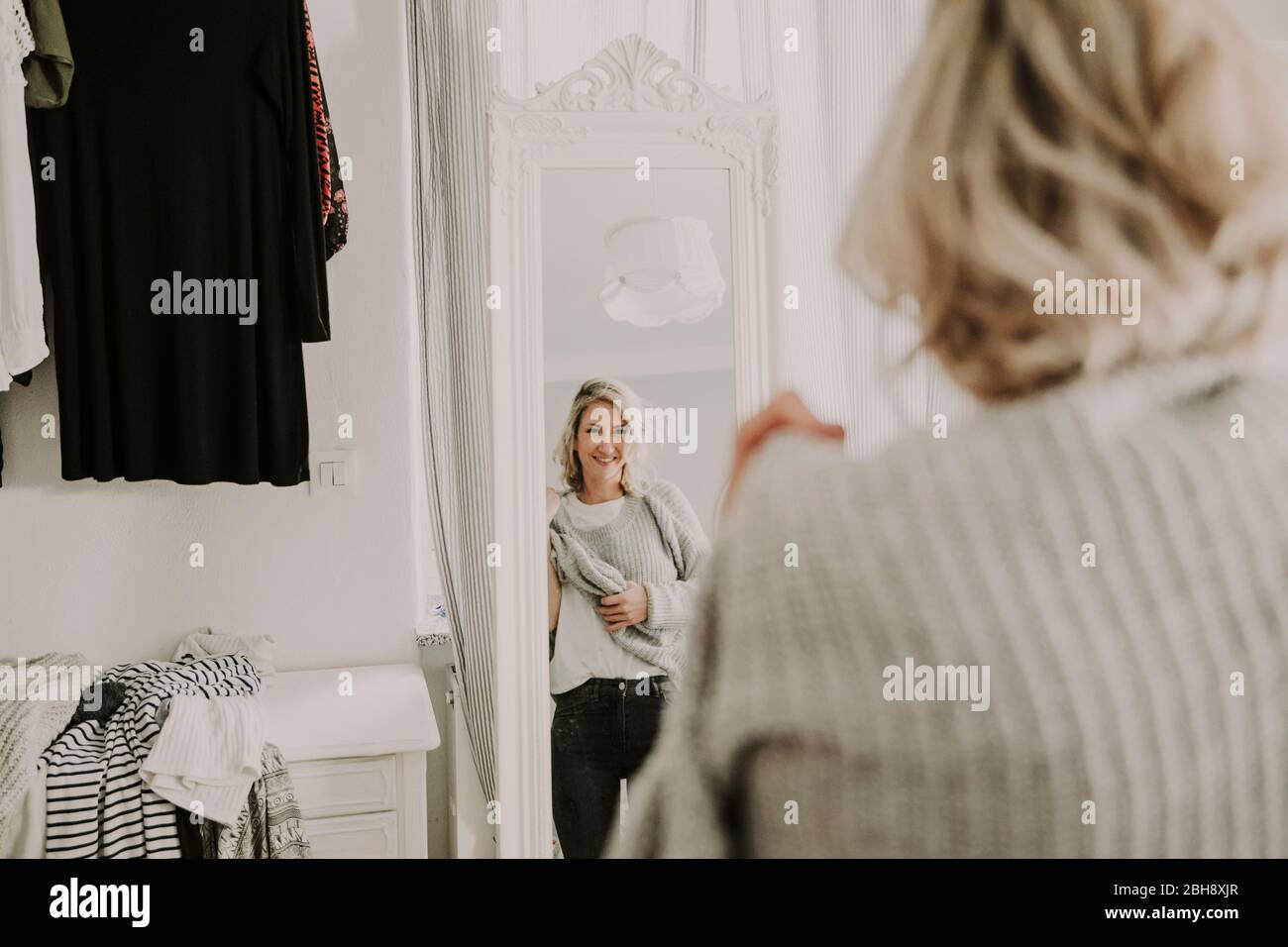 Frau steht vor dem Spiegel, kleidet sich an Banque D'Images