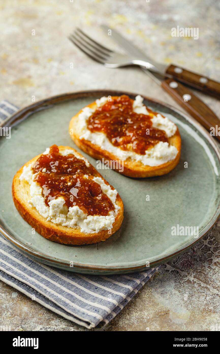 Canape ou crostini avec baguette grillée, fromage cottage, confiture de figues sur la plaque. Délicieux apéritif, apéritif idéal. Banque D'Images
