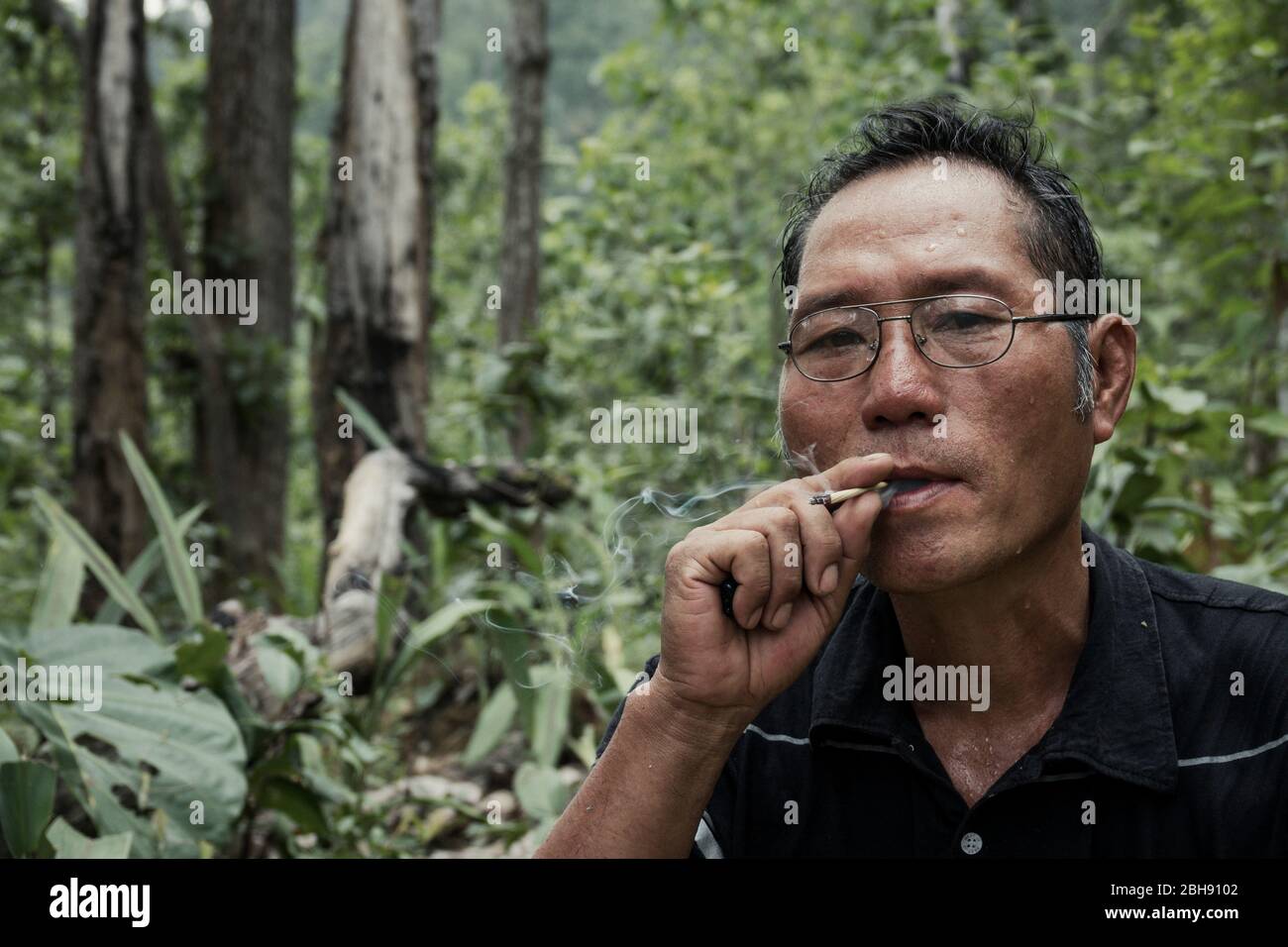 L'homme thaïlandais fume la cigarette thaïlandaise maison dans la jungle Banque D'Images
