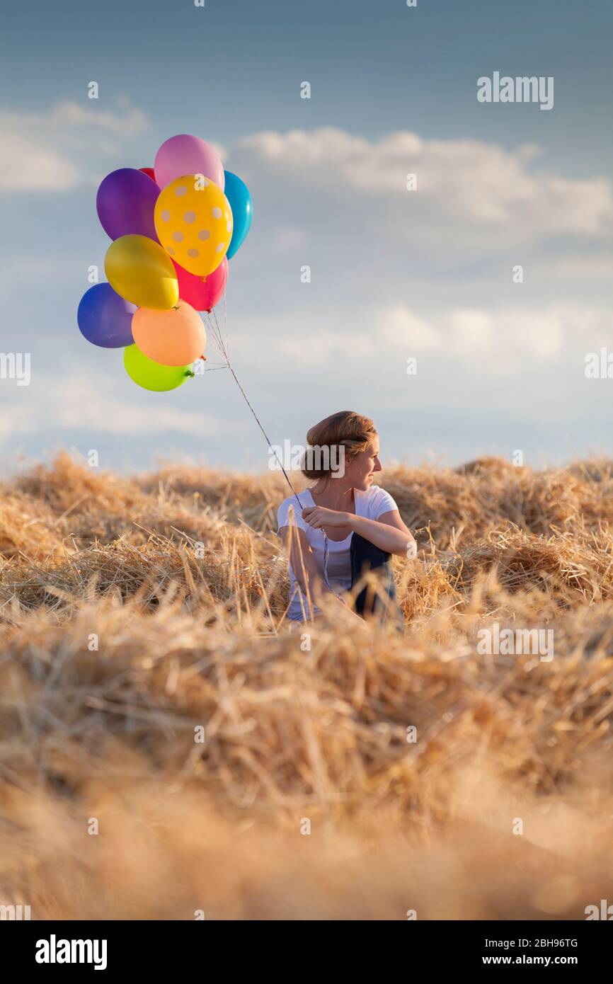 Jeune femme avec des ballons d'air colorés dans le champ de maïs propre Banque D'Images