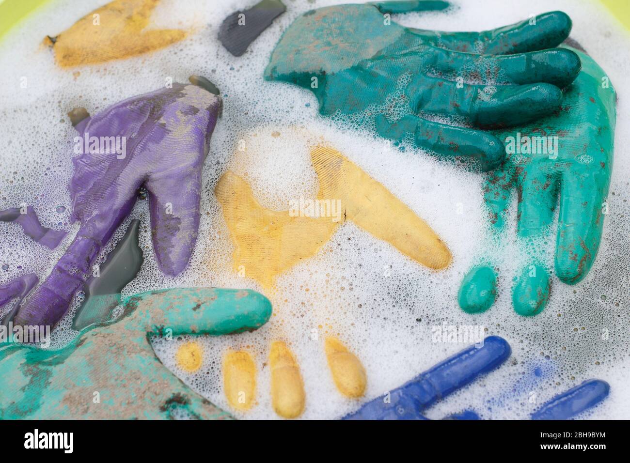 Laver les gants de jardinage sales dans une baignoire à l'eau chaude savonneuse. Banque D'Images