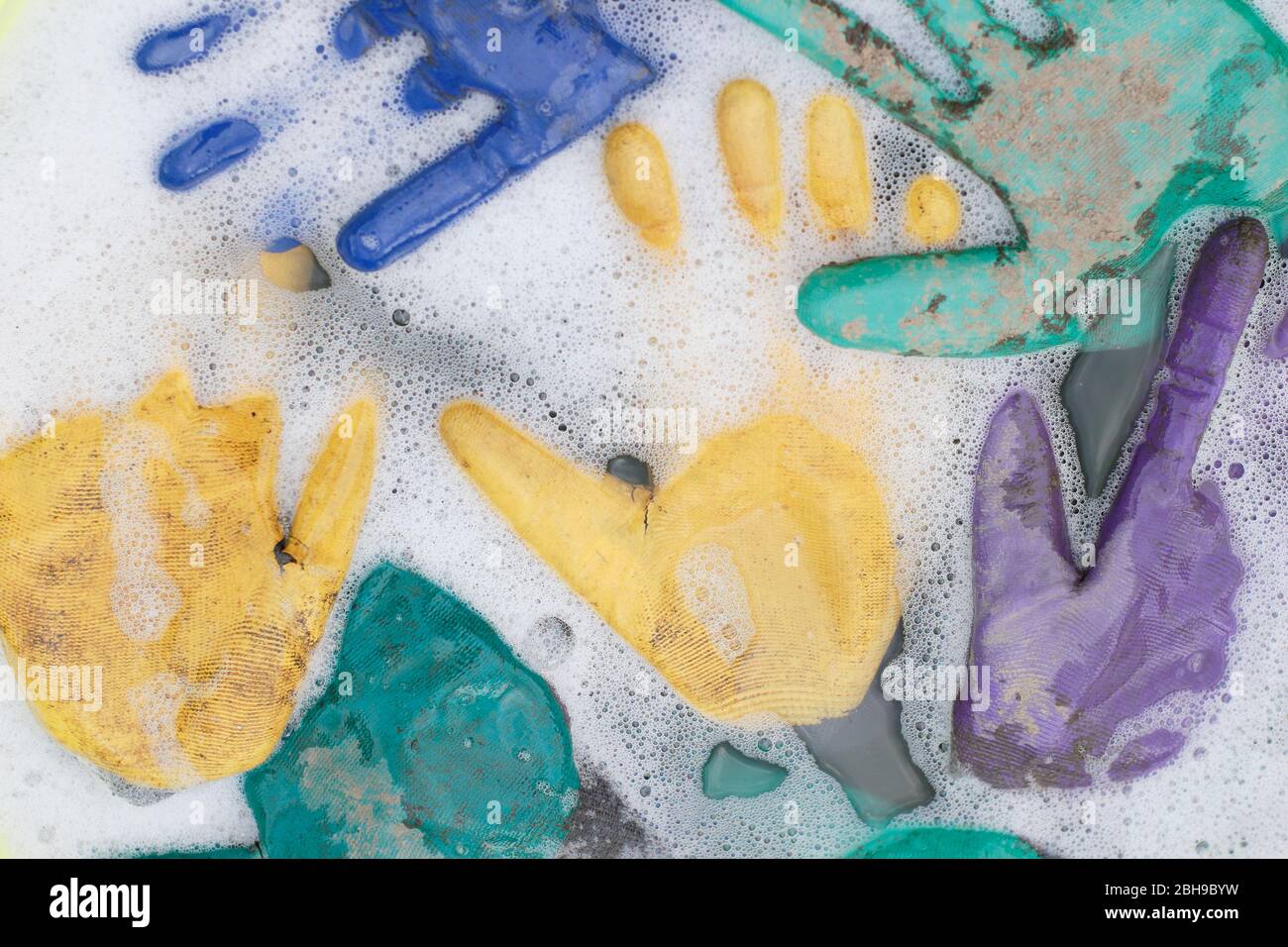 Laver les gants de jardinage sales dans une baignoire à l'eau chaude savonneuse. Banque D'Images