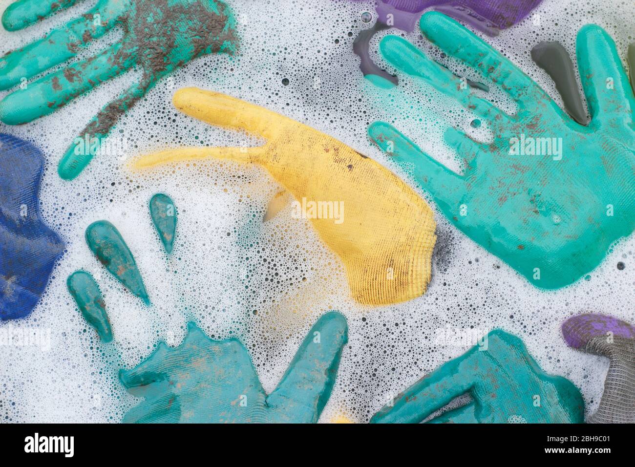 Laver les gants de jardinage sales dans une baignoire à l'eau chaude savonneuse. Banque D'Images