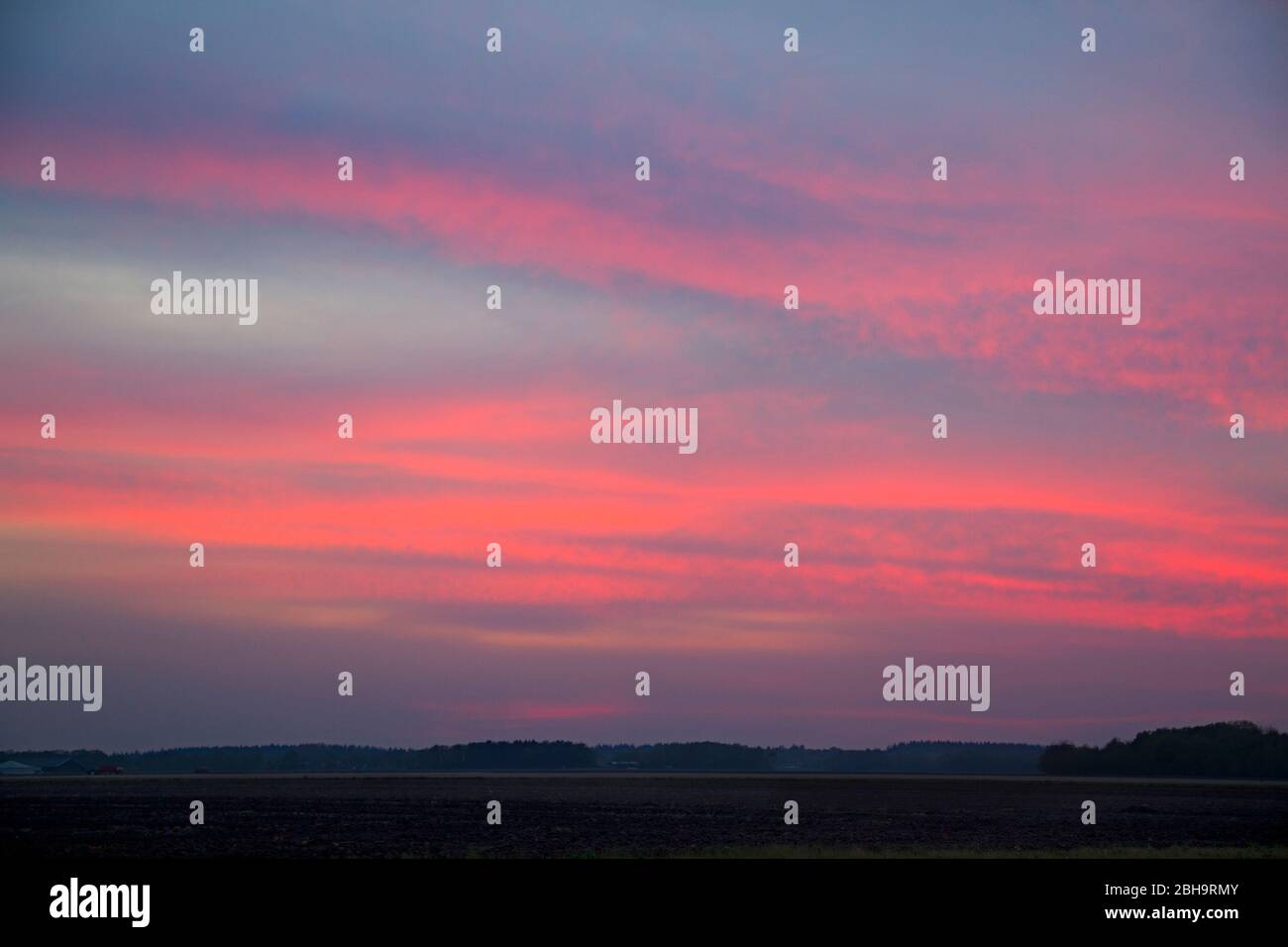 La tombée de la nuit dans le pays : nuages rouges sur un horizon sombre Banque D'Images
