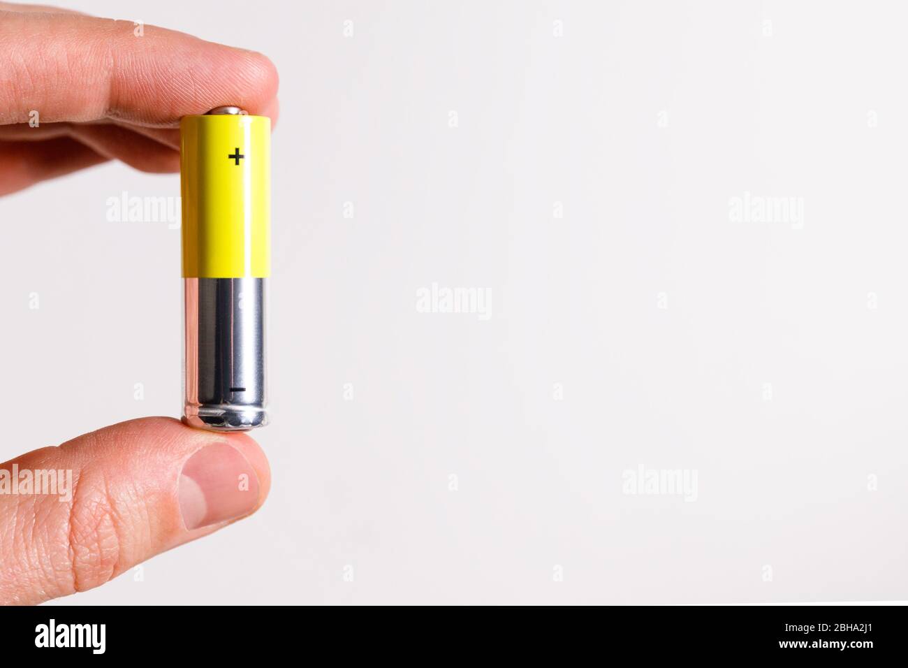 Main homme tenant pile alcaline AA taille, gros plan, isolé sur fond blanc avec espace de copie. Banque D'Images