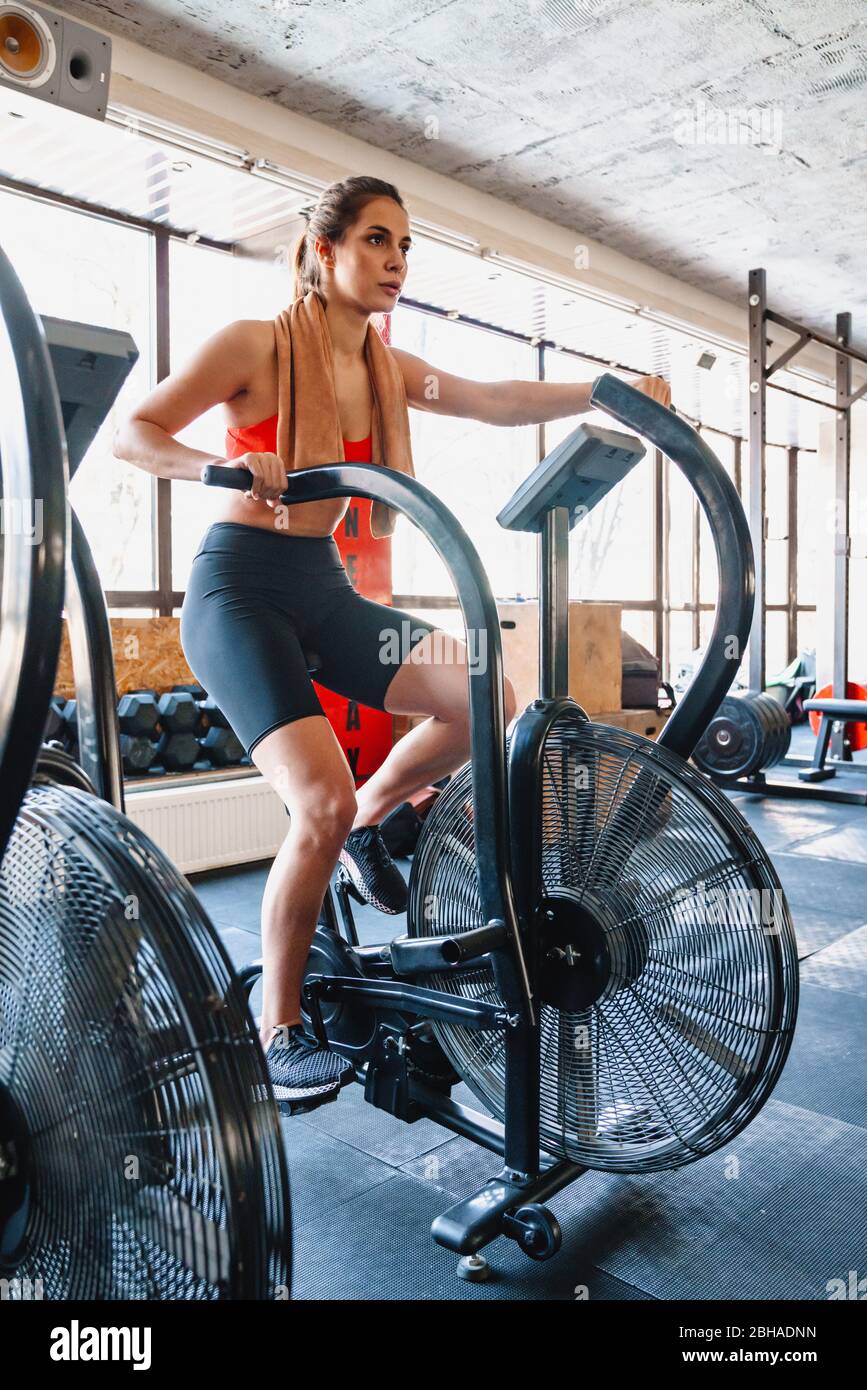 Jeune sportif confiant exerçant sur une machine elliptique à la salle de gym Banque D'Images