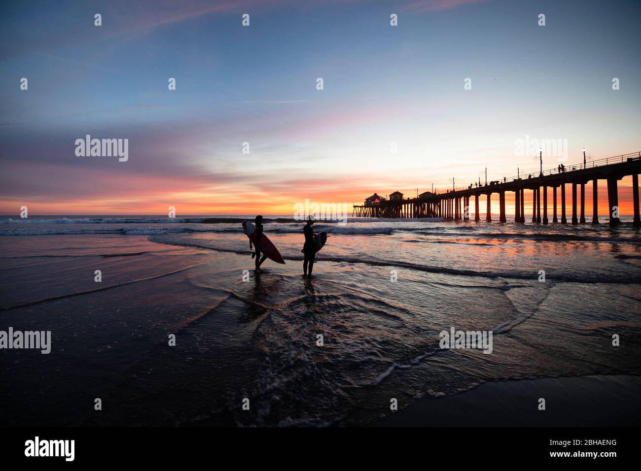 Silhouettes de surfeurs à Huntington Beach Pier au coucher du soleil, Californie, États-Unis Banque D'Images