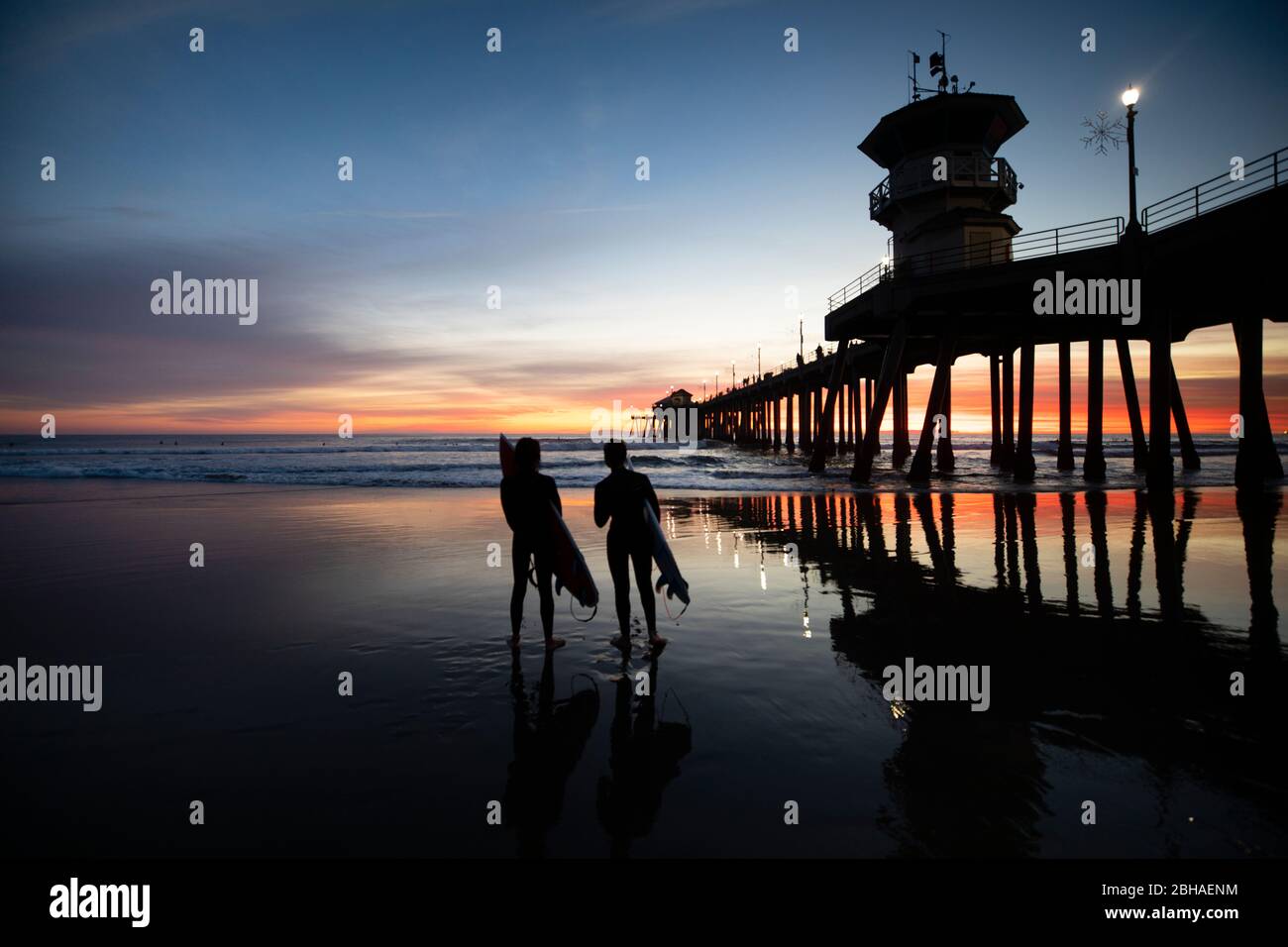 Silhouettes de surfeurs à Huntington Beach Pier au coucher du soleil, Californie, États-Unis Banque D'Images
