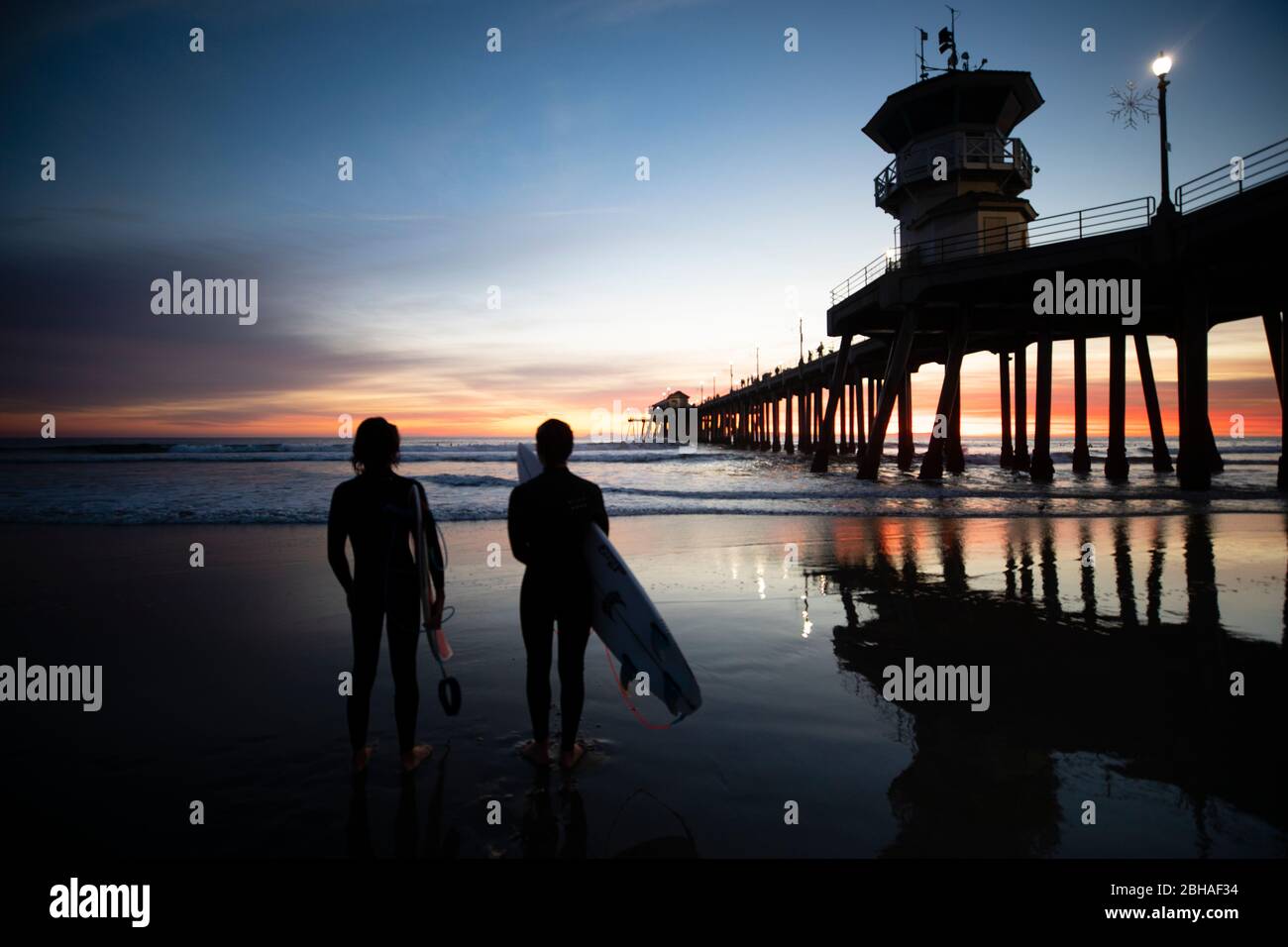 Silhouettes de surfeurs à Huntington Beach Pier au coucher du soleil, Californie, États-Unis Banque D'Images