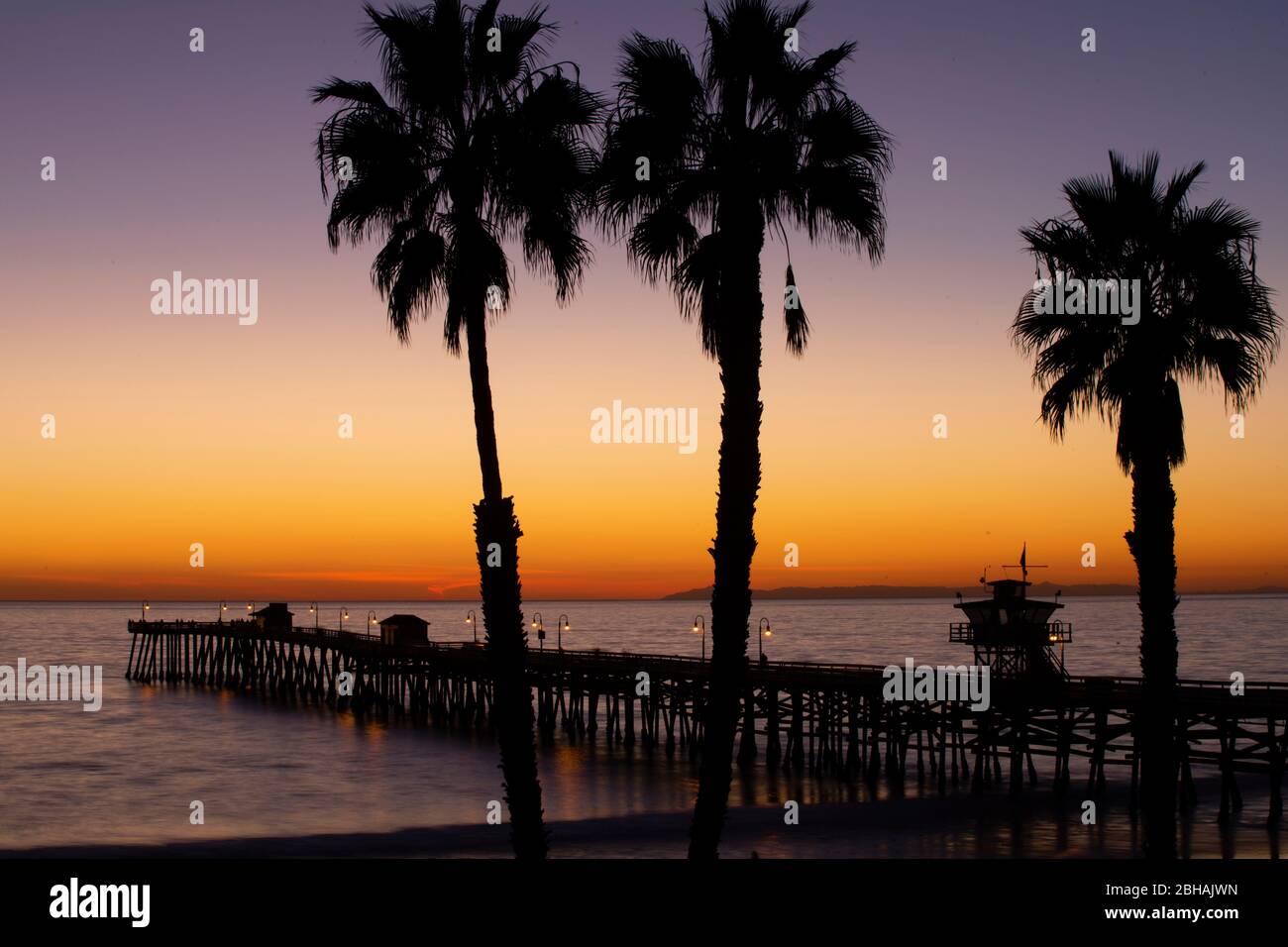 Huntington Beach Pier et palmiers au coucher du soleil, Californie, États-Unis Banque D'Images