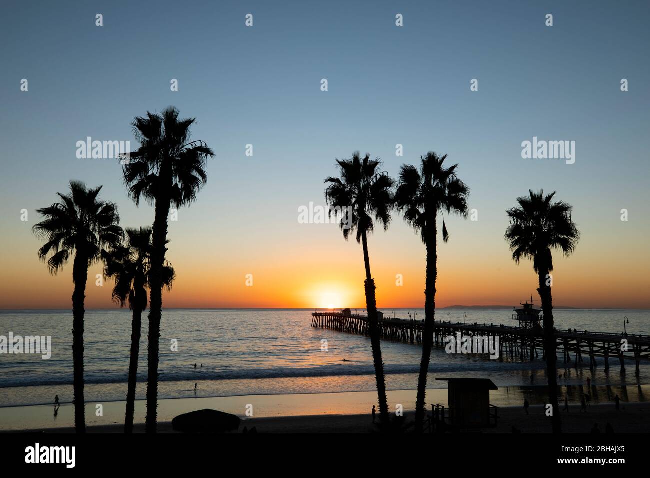Huntington Beach Pier et palmiers au coucher du soleil, Californie, États-Unis Banque D'Images