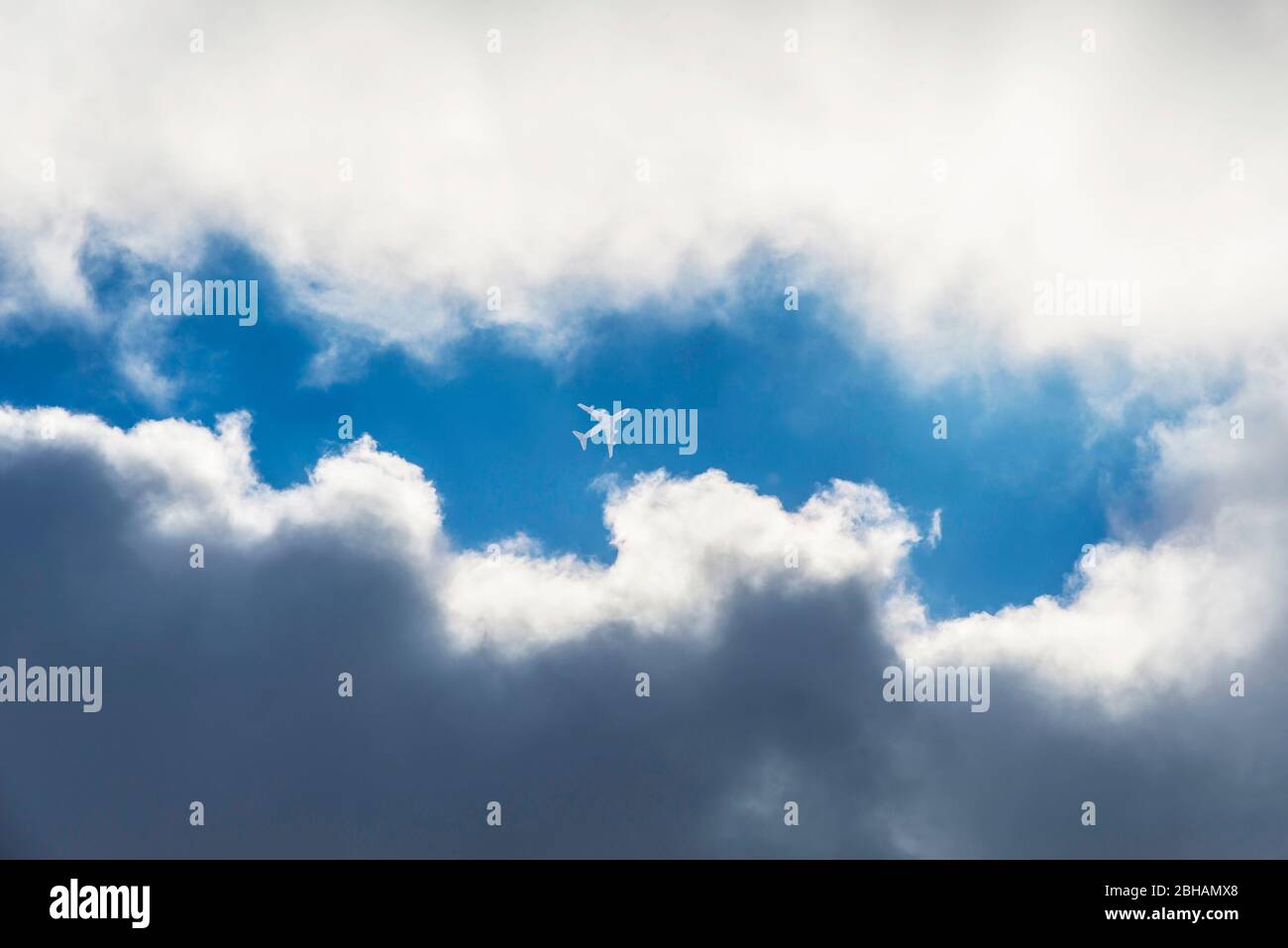 Avion de passagers dans un espace de nuages sur un ciel fortement couvert Banque D'Images