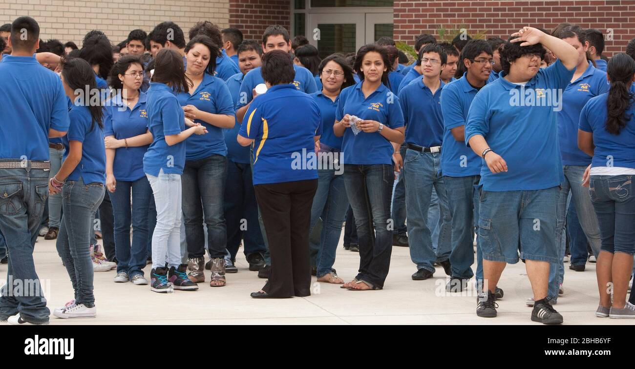 Pharr Texas USA, 13 mai 2010: Les élèves du lycée de la première école secondaire du district scolaire Pharr-San Juan-Alamo se mêlent à l'extérieur tout en attendant leurs bus scolaires sur le campus de l'extrême sud du Texas. Les élèves doivent porter les chemises bleues uniformes pendant la journée d'école. L'école donne aux étudiants la possibilité de gagner du crédit d'université tout en prenant des cours de lycée avancés et d'obtenir un départ de tête sur l'université. ©Bob Daemmrich Banque D'Images
