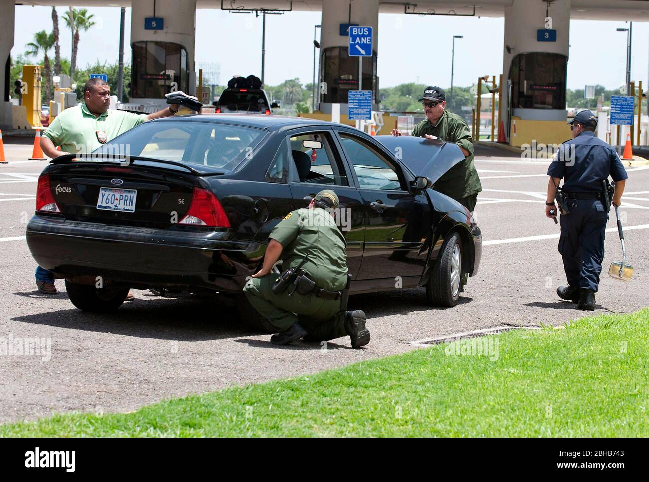 Laredo, Texas États-Unis, 14 juillet 2010: Des agents fédéraux, y compris la patrouille frontalière des États-Unis (vert), les douanes américaines (bleu) et les adjoints du shérif du comté de Webb inspectent les voitures en direction du Mexique au port d'entrée de Laredo, au Texas. Les agents sont à la recherche d'argent et de drogues qui se dirigent vers le Mexique à la suite de la violence accrue et du trafic de drogues le long de la frontière. ©Marjorie Kamys Cotera/Bob Daemmrich Photographie Banque D'Images